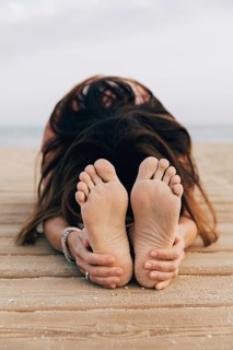 Unrecognizable woman practicing yoga on a beach. The yoga pose shown is a close-up of the Seated