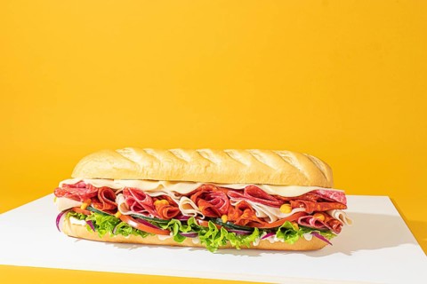 Minimalist composition of a complete sandwich, with layers of meat and fresh vegetables, captured