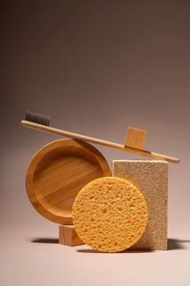 A bamboo toothbrush, eco-friendly toiletries, sponges, and soap are elegantly arranged on a neutral