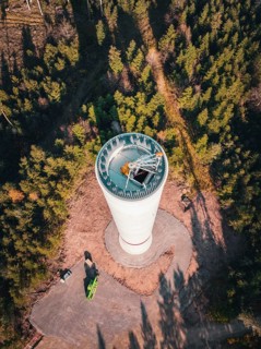 A bird's eye view of a wind turbine under construction surrounded by dense forest, Windrad Bau,