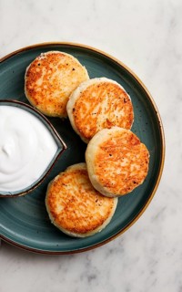 Fried, Cottage cheese pancakes, with sour cream, Cheesecakes, on a marble table, top view, no
