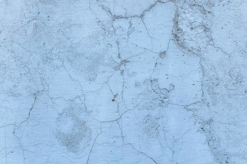 A close-up view of a weathered concrete surface displaying intricate cracks and texture, set in