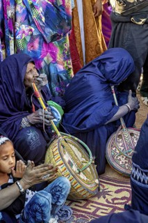 People play traditional instruments accompanied by children in a colourful setting, Traditional