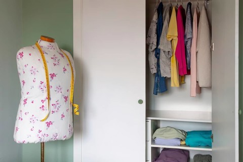 A well-organized closet with colorful clothes hanging neatly and folded on shelves, alongside a