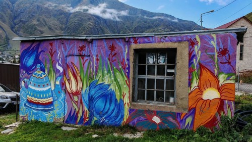 Artfully painted house against a mountain backdrop, vivid colors, Caucasus, Georgia