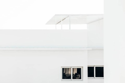 A modern minimalist architectural design featuring a white building with sharp clean lines, large