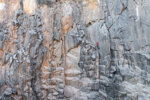 Two climbers tackles a challenging rock face using traditional climbing techniques. The scene