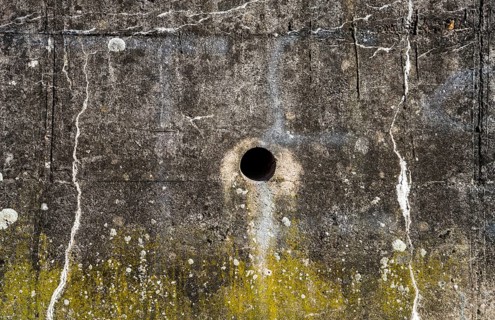 Old concrete wall with cracks, structures and green moss
