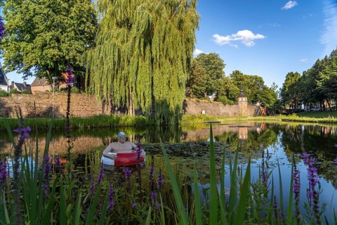 Frog pond with sculpture of Paul, the floating tyre man and the town wall with guard tower in Rees,