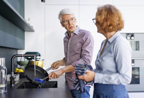 Symbolic photo. An elderly couple stand in the kitchen and do the washing up together. Berlin, 13