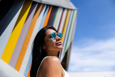 A stylish woman wearing a colorful outfit poses confidently against a backdrop of modern