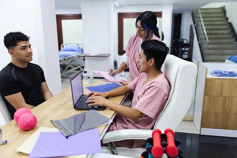 A physiotherapy session in an Ecuadorian clinic. A patient consults with two professionals in