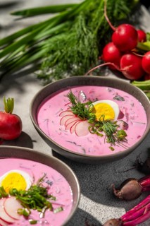A refreshing bowl of cold beetroot soup served with sliced radishes, hard-boiled eggs, and fresh