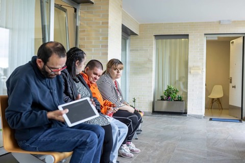 A group of individuals sitting and interacting in a mental health residence, fostering a sense of