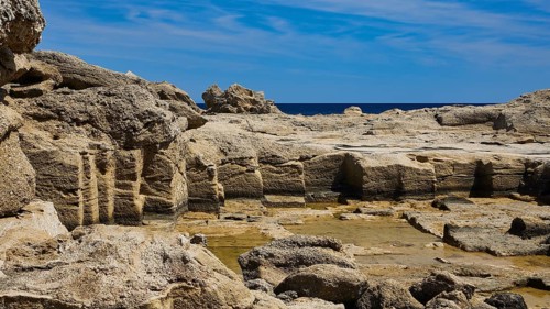 Rough rocky landscape by the sea under a sunny sky, Oasis Beach, East Coast Rhodes, Rhodes,