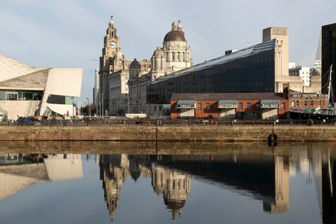 The Three Graces iconic waterfront landmark buildings reflected in water, Canning Dock, Liverpool,