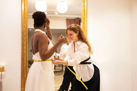 A tailor ensures a perfect fit by measuring a client waist in an elegant bridal fitting room. The