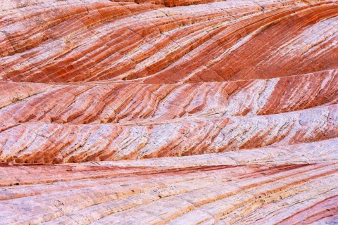 A close-up of naturally textured red rock sediment layers, showcasing vibrant striations and