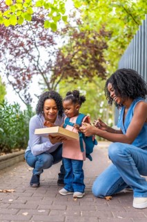 Vertical portrait of african three generation females in the city enjoying picking up a girl from