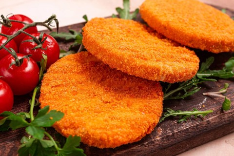 Crispy fried fish cutlets, fish burgers, on a wooden chopping board, with arugula and cherry