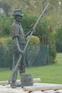 Monument to historic raftsmanship, modern art, bronze sculpture, man on raft with pole, barrel,