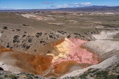Colored sedimentary rock formations in shades of red, pink, orange and yellow, eroded gorge in