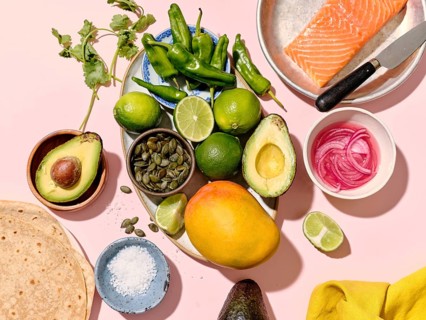 Top view of taco ingredients arranged neatly on a pink surface for a culinary concept. Items