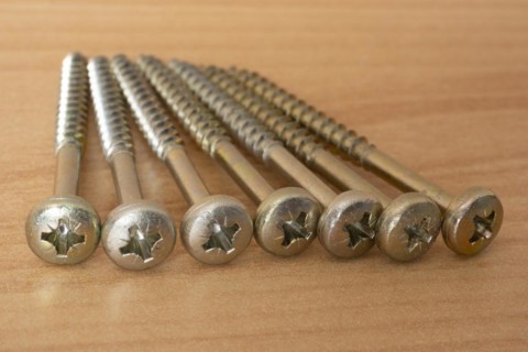 Phillips screws on wooden background, wood screws