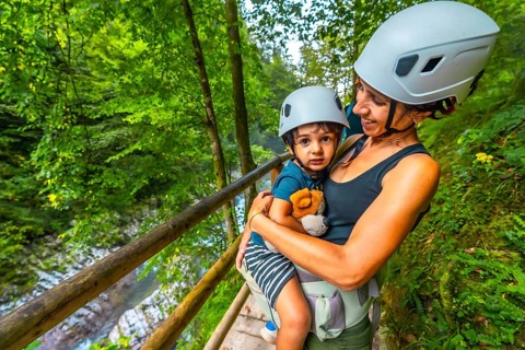Mother carrying her son in a baby carrier while visiting the scenic vintgar gorge near bled,