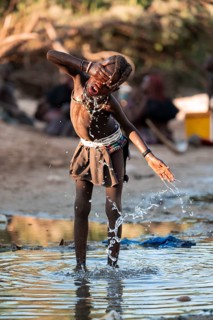 Himba child washing with water on a river, traditional Himba, Kaokoveld, Kunene, Namibia
