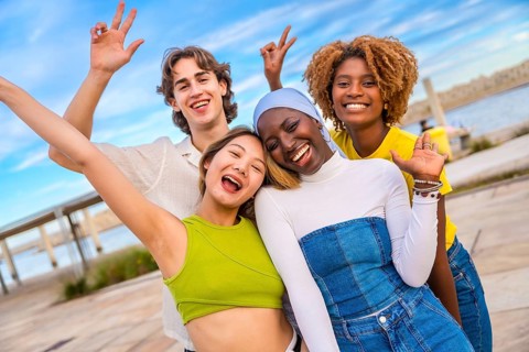 Multi-ethnic friends gesturing peace while smiling in an urban space