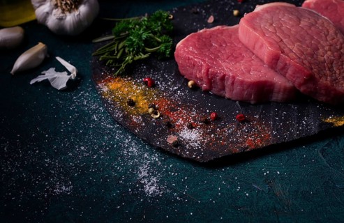 Fresh raw beef meat, Medallions, on black slate, with spices, close-up, horizontal