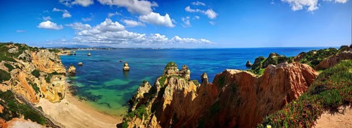 Panoramic view of a rocky coastal landscape, beach, lush green vegetation with clear blue sea and