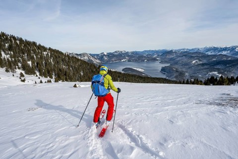 Skiers skiing down the Simetsberg, view of Walchensee and mountain panorama, Estergebirge, Bavarian
