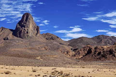 Picture of a dry desert landscape with a majestic, rocky mountain under a clear blue sky, The