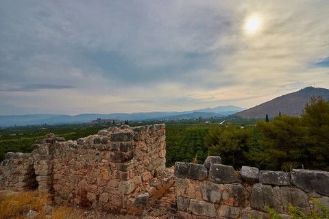Stone walls and ruins with a cloudy sky and mountains in the distance, Tiryns, ancient city in