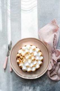 A beautifully presented homemade lemon cake on a ceramic plate beside a pink napkin, fork, and