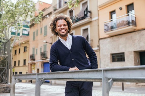 A man enjoys a relaxing moment outside a coworking space in Barcelona. He leans casually on a