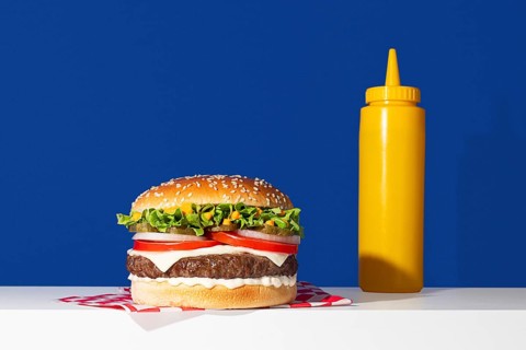 A vibrant image showcasing a delicious cheeseburger paired with a bright yellow mustard bottle, set