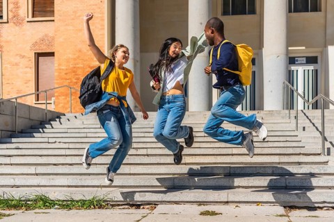 Three multi-ethnic cheerful university students jumping celebrating at the campus