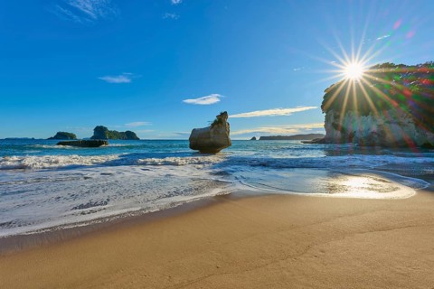 Rocky beach under a clear blue sky with sun, Cathedral Cove, Coromandel, Canterbury, North Island,