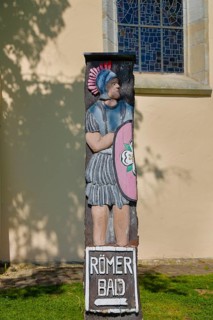 Signpost, signpost to the Roman baths, Roman estate, Protestant town church behind, replica of a