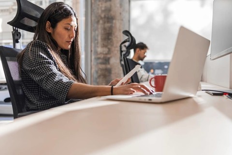 Two coworkers engaged in teamwork at a modern office The woman works on a laptop, indicating