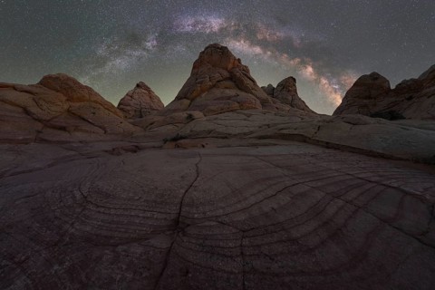 A breathtaking night sky view featuring the Milky Way over textured rock formations in the Utah