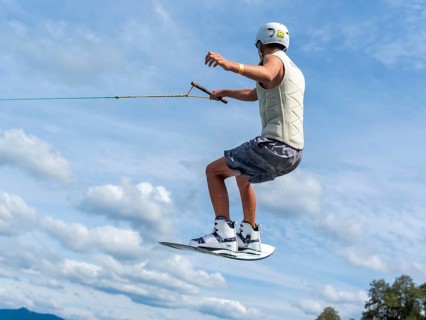 Young man jumping and flying with wakeboard, water sports and water skiing in the wakepark