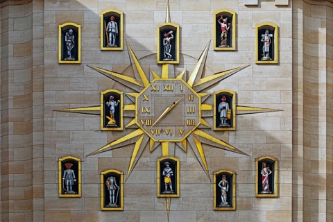 Large golden wall clock with twelve figures at the back of the Dynasty Palace, Brussels, Belgium