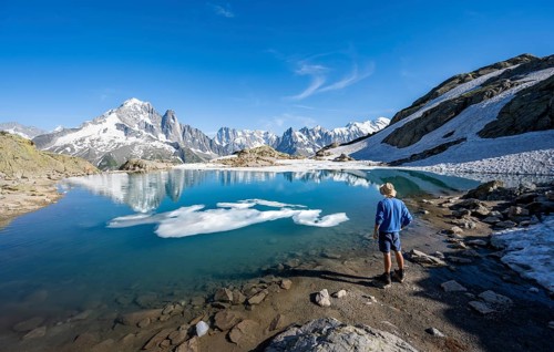 Mountaineer in front of mountain landscape with mountain lake, tourist at Lac Blanc with water