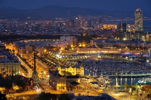 Aerial view of Barcelona city skyline with city traffic and port with yachts illuminated in the
