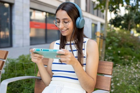 A cheerful woman enjoys her day outdoors in the city, sitting on a bench while wearing headphones