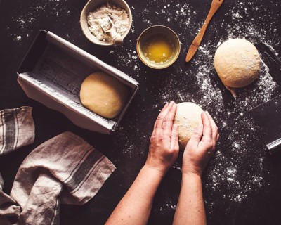 A person gently prepares homemade sliced bread dough in a rustic kitchen setting. The scene